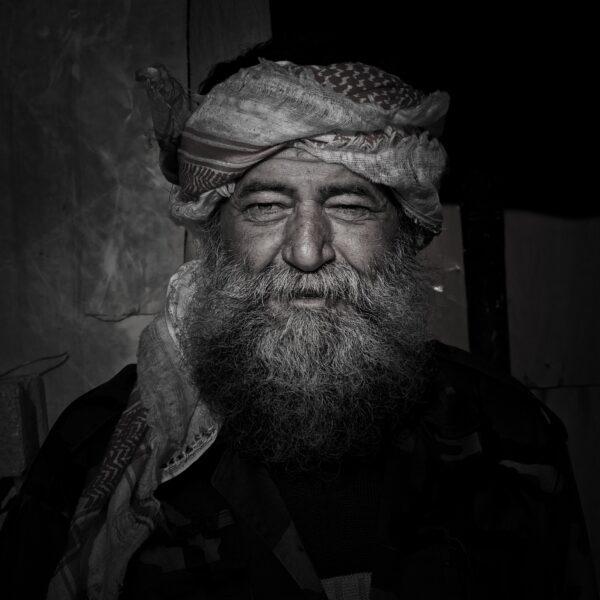 Il s'agit d'une photographie d'art. Disponible à la vente sur le site de Paragone Concept. Elle représente le portrait d'un homme. Celui ci étant un syrien, agent immobilier de son état, qui fut obligé de devenir soldat dans son pays en guerre.